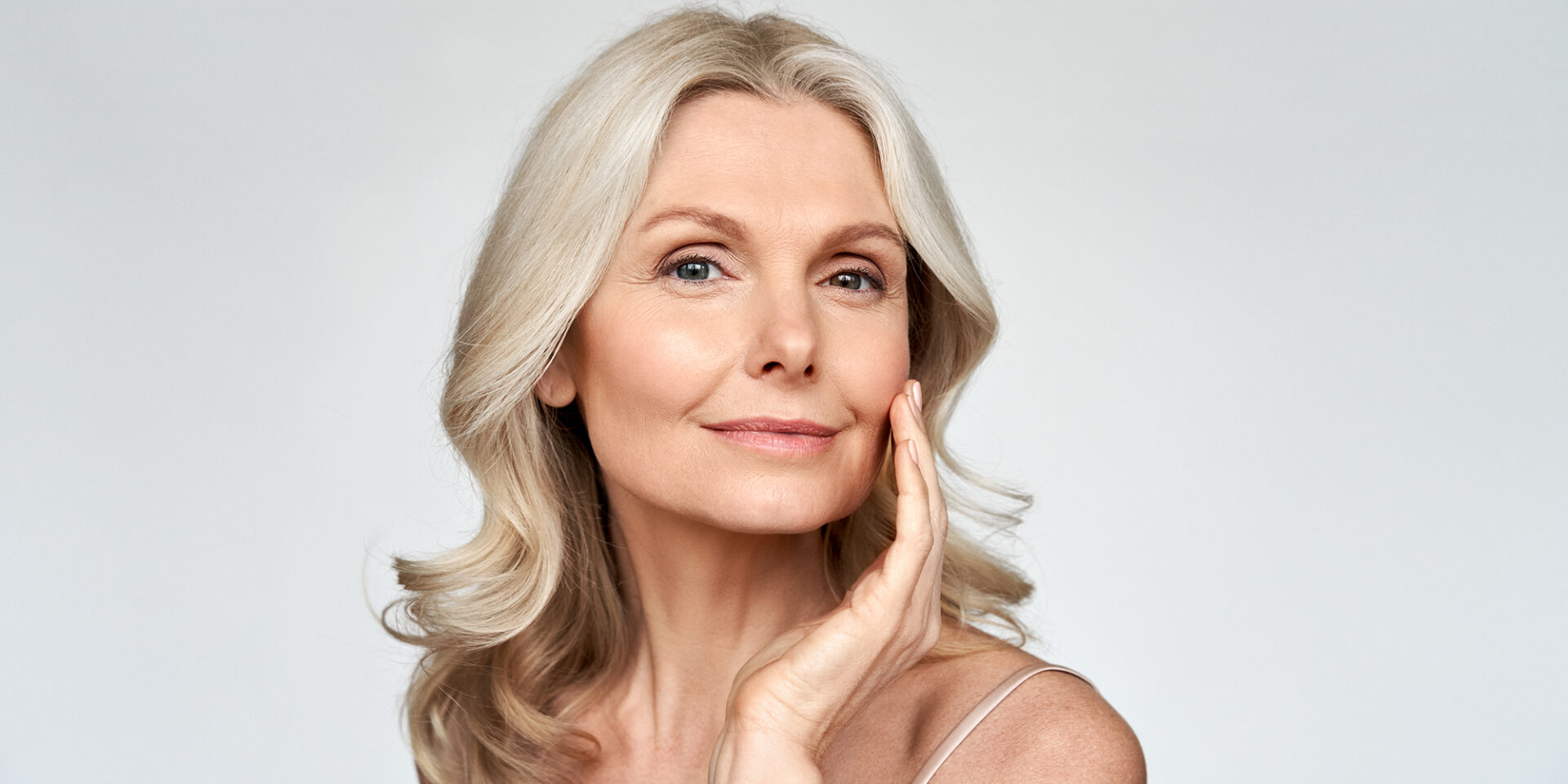 Beautiful gorgeous 50s mid aged mature woman looking at camera isolated on white. Mature old lady close up portrait. Healthy face skin care beauty, middle age skincare cosmetics, cosmetology concept