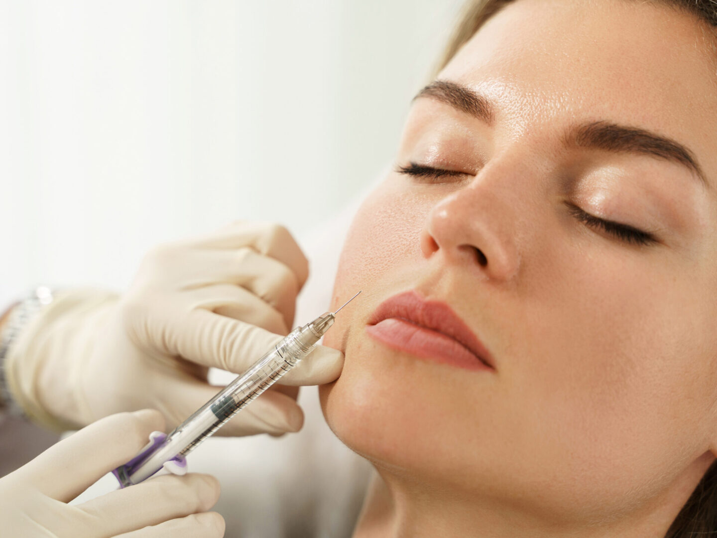 Female client during facial filler injections in aesthetic medical clinic