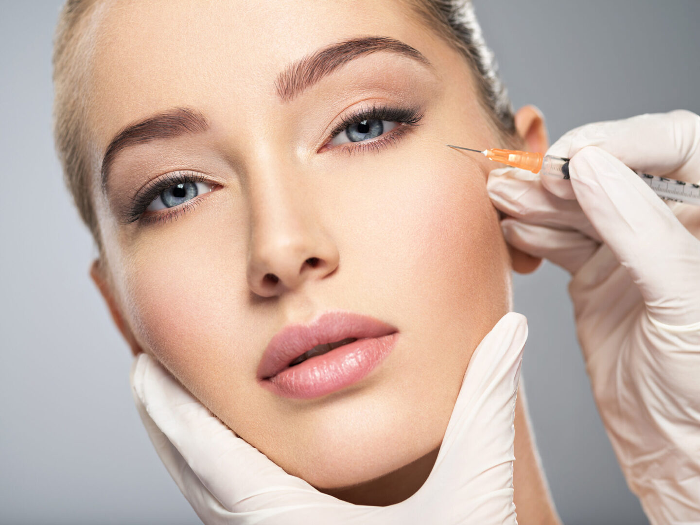 Woman getting cosmetic injection of botox in cheek, closeup. Woman in beauty salon. plastic surgery clinic.